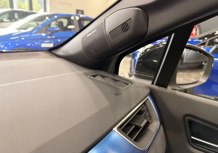 Vue intérieure côté droit du tableau de bord gris avec haut-parleur Harman Kardon et insert bleu sur Renault Symbioz E-Tech 2026.