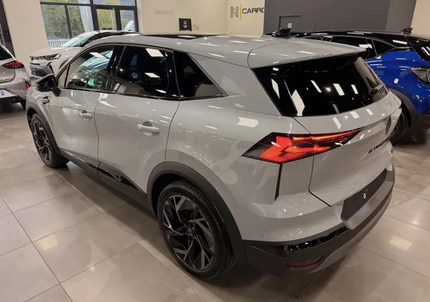 Vue 3/4 arrière droite du Renault SYMBIOZ gris Rafale avec feux arrière allumés et jantes noires en concession.