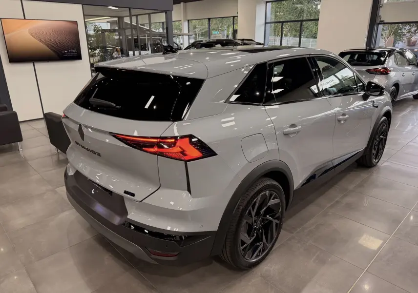 Vue 3/4 arrière droite du Renault SYMBIOZ gris Rafale en showroom, avec feux arrière LED et jantes noires distinctives.