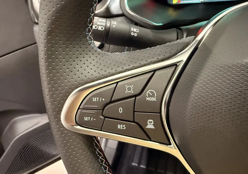 Gros plan sur les commandes gauche du volant perforé noir du Renault SYMBIOZ E-Tech 2026, avec surpiqûres tricolores.