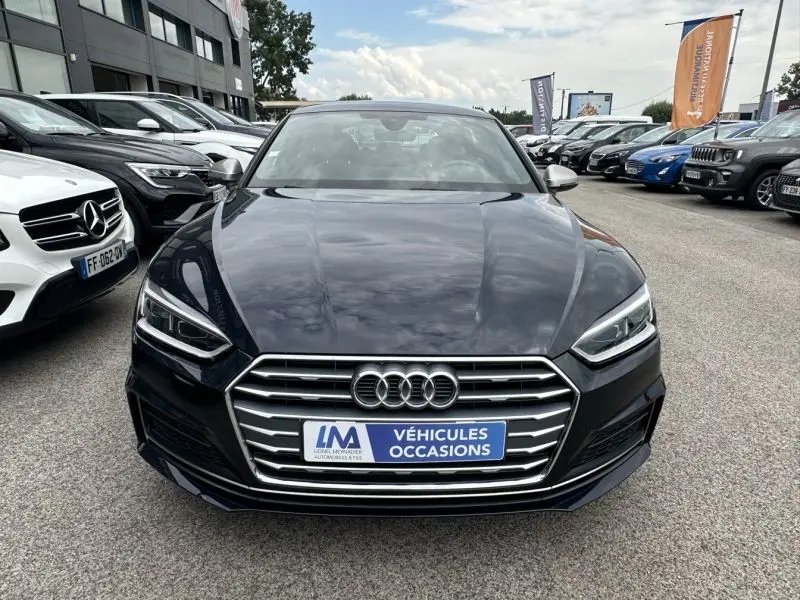 Vue frontale d'une Audi A5 Sportback bleu lunaire métal avec calandre chromée et phares LED allumés.