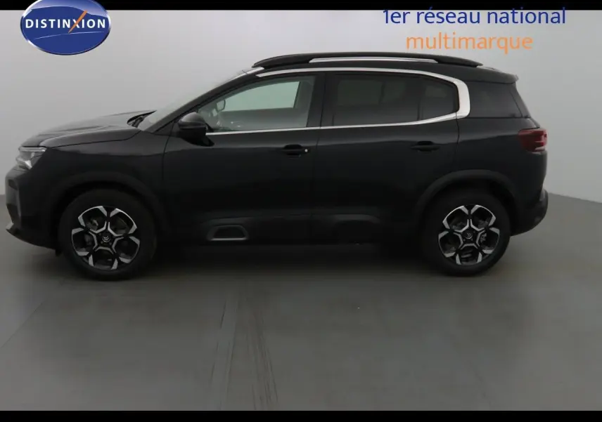 Vue 3/4 arrière d'un Citroën C5 Aircross noir métal avec jantes bi-ton et barres de toit visibles.
