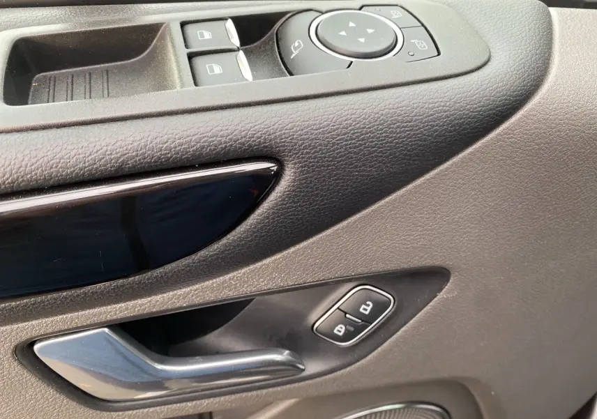 Gros plan sur la poignée intérieure côté gauche en plastique gris et les commandes de vitres du Ford Tourneo Custom 2020.