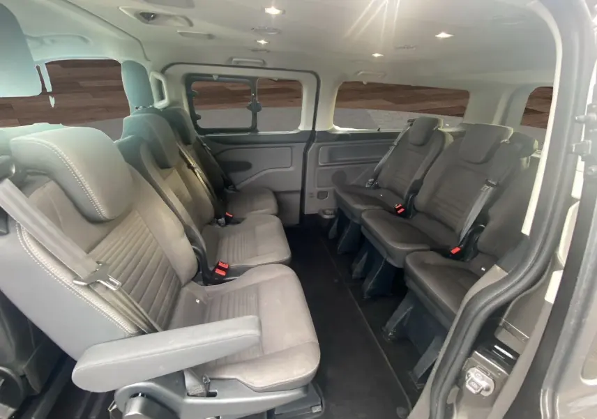 Intérieur du Ford Tourneo Custom gris magnetic, vue latérale droite sur les sièges passagers en rangées face à face.