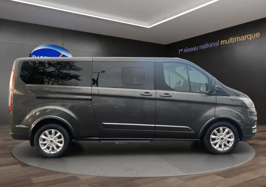 Ford Tourneo Custom gris magnetic vu de profil côté gauche, avec vitres teintées et jantes alliage.