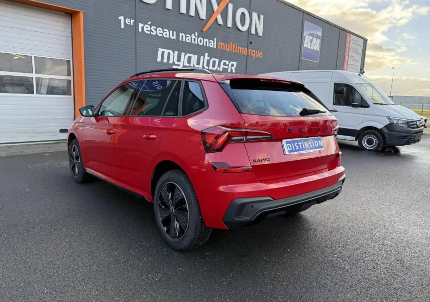 Vue 3/4 arrière droite d'un SKODA KAMIQ Monte-Carlo rouge velvet métallisé avec jantes noires et vitres surteintées.