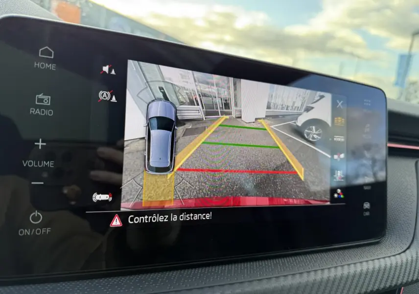 Écran tactile intérieur affichant la caméra de recul du Skoda Kamiq rouge Velvet, avec lignes de guidage colorées.