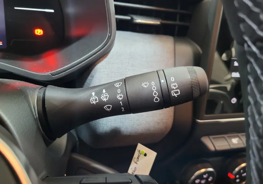 Gros plan sur la commande des essuie-glaces à gauche du volant dans l’habitacle gris foncé de la Renault Clio 2025.