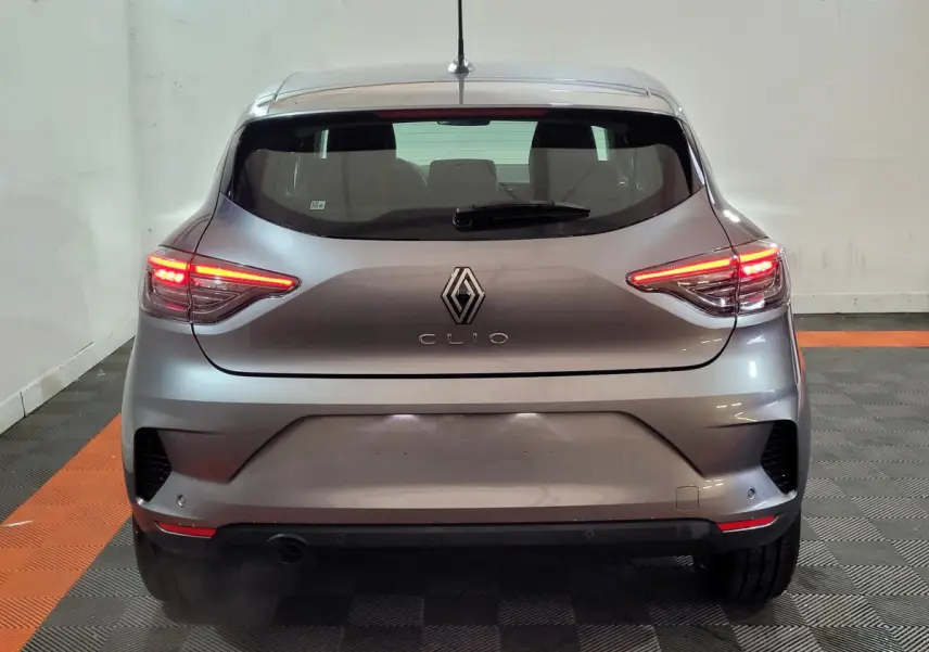 Vue arrière d'une Renault Clio gris foncé 2025 avec feux LED allumés, dans un garage au sol carrelé noir et orange.