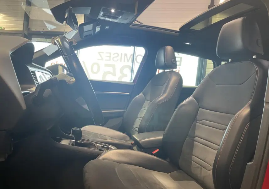 Intérieur du SEAT Ateca 2022 rouge, vue côté conducteur, sièges sport noirs avec surpiqûres contrastées et toit ouvrant.
