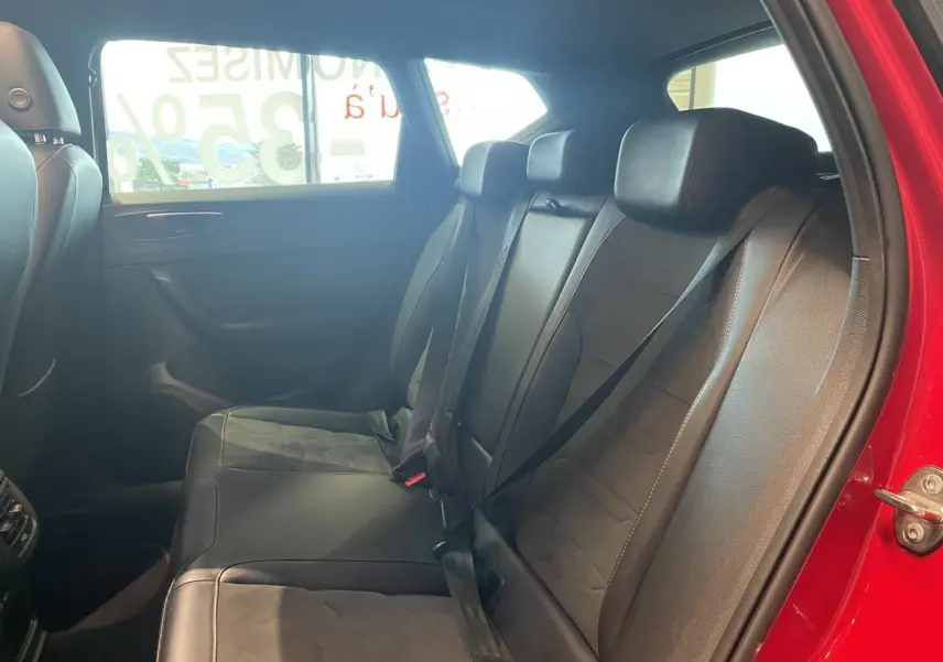 Vue intérieure côté droit des sièges arrière en cuir noir du SEAT Ateca rouge 2022, avec ceinture de sécurité attachée.