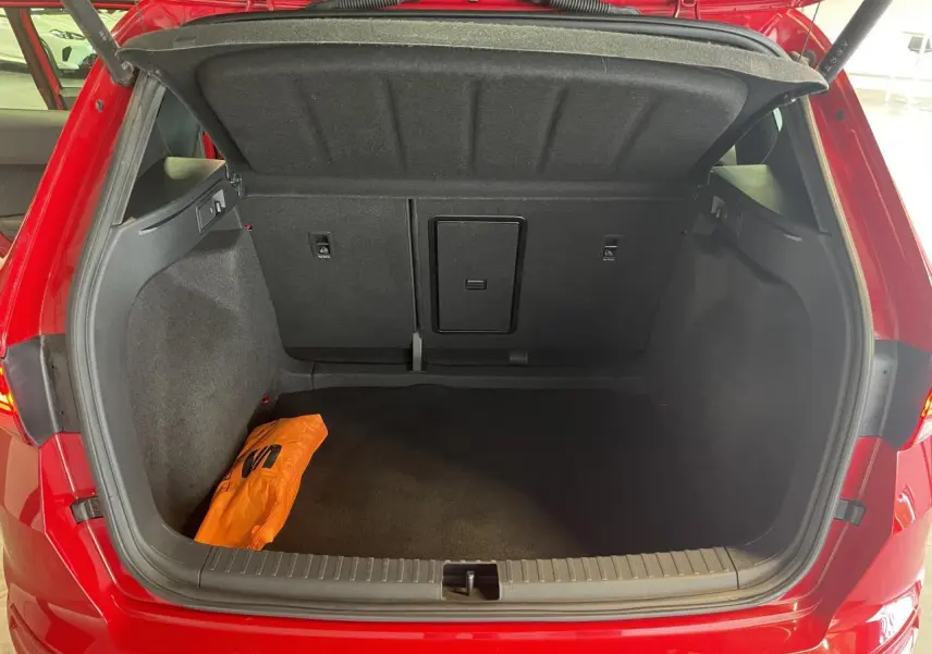 Coffre ouvert vu de l'arrière d'un SEAT Ateca rouge 2022, avec un sac orange à l'intérieur.