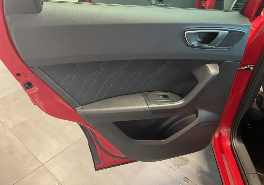 Vue rapprochée de la porte arrière gauche rouge du SEAT Ateca 2022, avec garniture noire et bouton de vitre électrique.