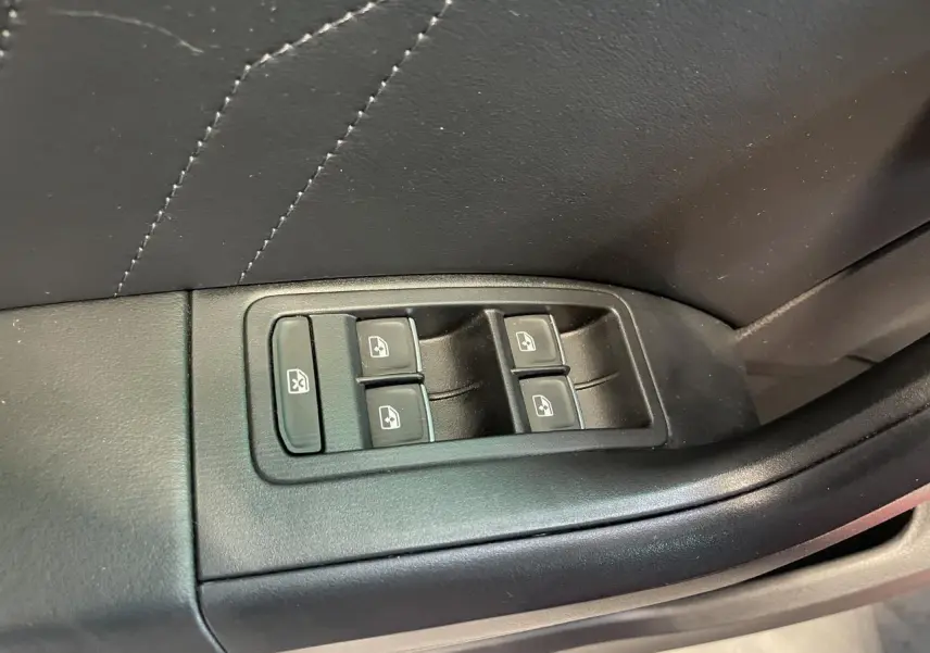 Commande des vitres électriques sur la portière intérieure noire du SEAT Ateca rouge, vue en gros plan.