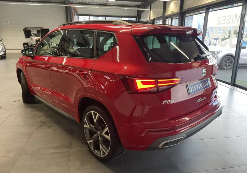 Vue 3/4 arrière droite d'un SEAT Ateca rouge 2022 avec feux allumés et jantes alliage distinctives en concession.