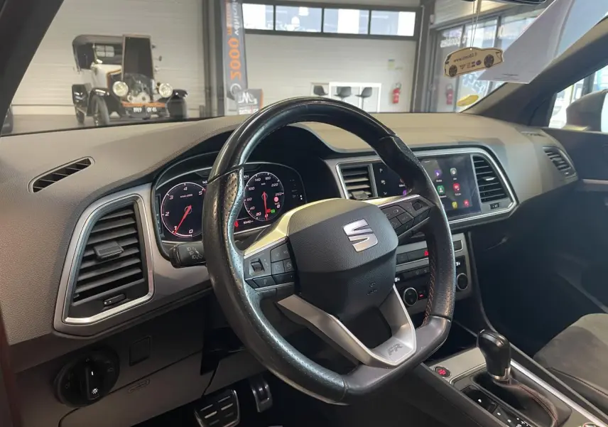 Vue intérieure du poste de conduite du SEAT Ateca rouge 2022, volant cuir avec logo FR et tableau de bord digital.