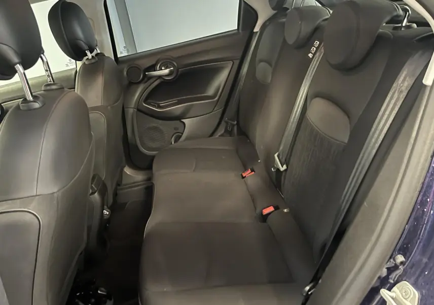Vue intérieure côté droit des sièges arrière noirs du Fiat 500X 2024 avec appuie-têtes et ceintures visibles.