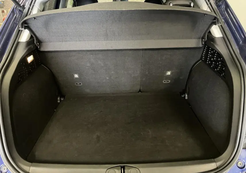 Coffre ouvert vu de l'arrière d'une Fiat 500X bleu, montrant l'espace de rangement et la plage arrière noire.