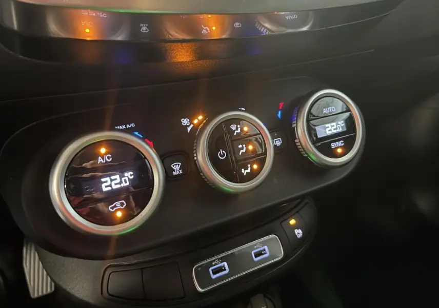 Gros plan sur la console centrale du Fiat 500X 2024 montrant les commandes de climatisation automatique bi-zone et ports USB.