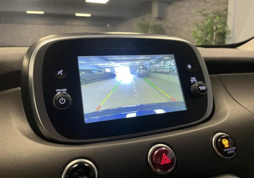 Écran multimédia affichant la caméra de recul d'une Fiat 500X bleu, vue intérieure du tableau de bord.