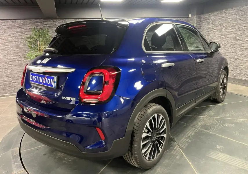 Fiat 500X bleu métallisé vue 3/4 arrière droit, jantes alliage 17 pouces et vitres surteintées.
