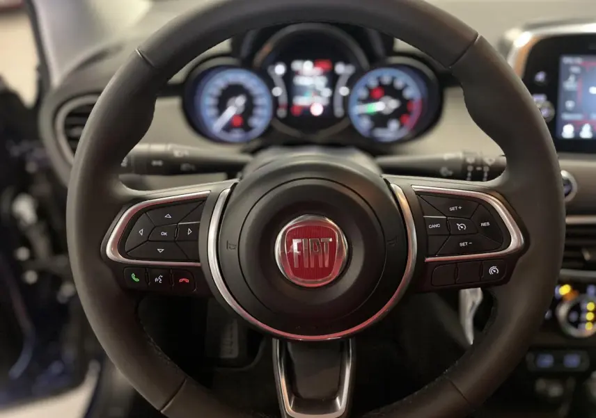 Volant Fiat 500X 2024 en cuir noir avec commandes intégrées, cadrans lumineux et tableau de bord gris titane.