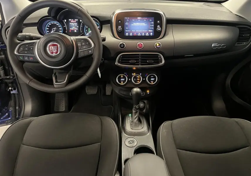 Intérieur de la Fiat 500X 2024 bleu, vue de face sur le tableau de bord avec écran tactile et volant multifonction.