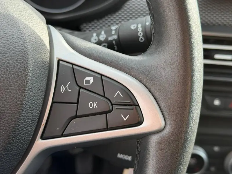 Gros plan sur les commandes au volant à gauche du Dacia Jogger 2025, cuir noir et boutons multifonctions noirs.