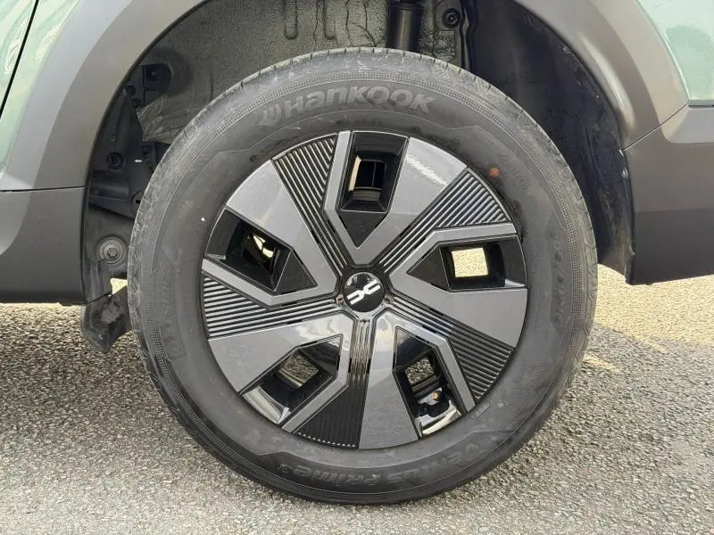 Gros plan sur la roue avant gauche du Dacia Jogger 2025 en Vert Cèdre métallisé avec jante au design noir et gris.