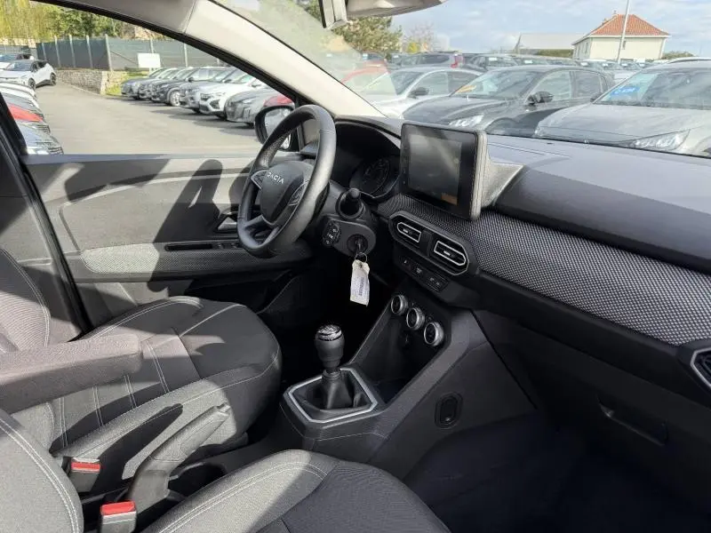 Vue intérieure côté conducteur du Dacia Jogger 2025, montrant le volant, la boîte manuelle et l'écran tactile central.