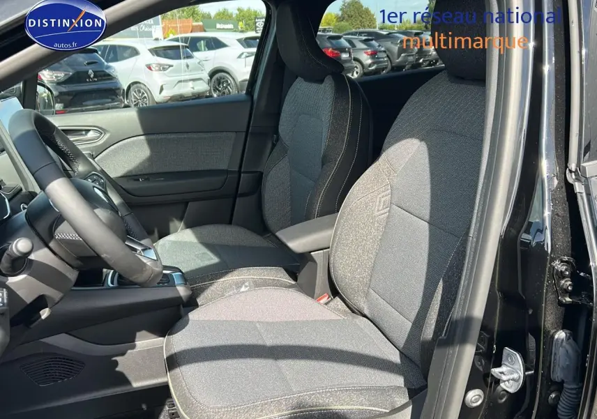 Vue intérieure côté conducteur du Renault Captur noir étoile 2025, mettant en valeur les sièges tissu et l'accoudoir central.