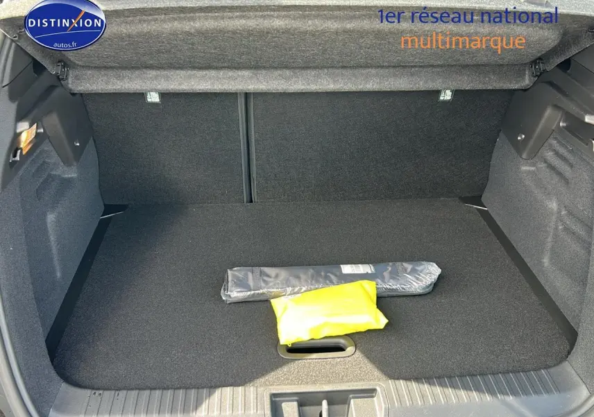 Coffre ouvert vu de l'arrière d'un Renault Captur noir Étoile 2025, avec tapis noir et objets emballés à l'intérieur.