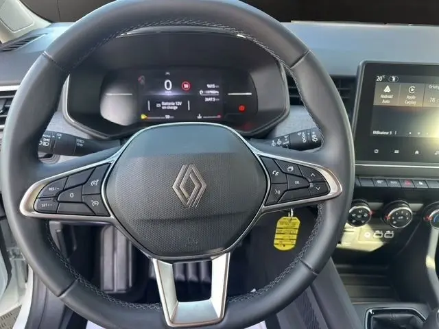 Vue rapprochée du volant en cuir synthétique noir de la Renault Clio blanche 2025 avec tableau de bord numérique et écran tactile central.