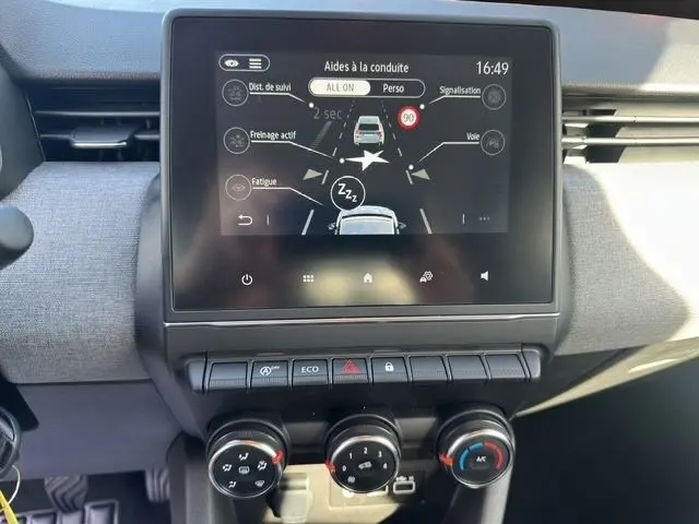 Vue rapprochée de l’écran tactile central affichant les aides à la conduite dans l’habitacle d’une Renault Clio blanche.