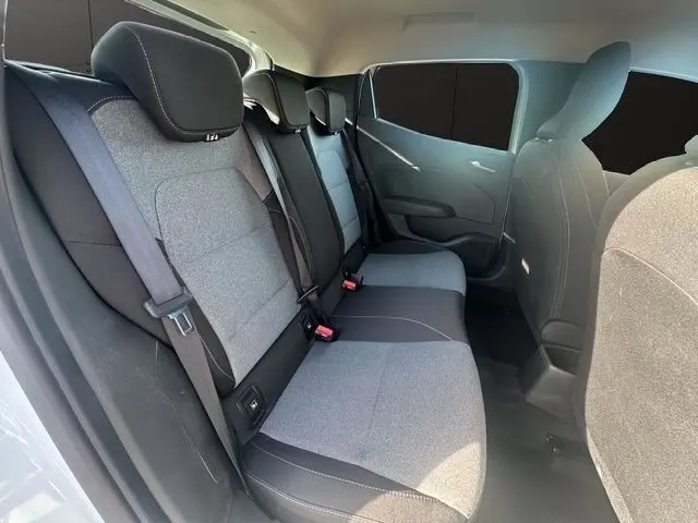 Vue intérieure du côté arrière droit de la Renault Clio blanche 2025, montrant la banquette 3 places en tissu bicolore gris et noir.
