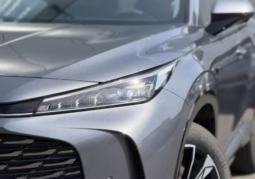 Gros plan sur l'avant droit gris métallisé du MG MOTOR EHS 1.5 Hybrid+ 224 Luxury avec phare LED et jante alliage.