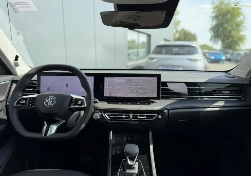 Vue intérieure avant du MG Motor EHS gris 2026, tableau de bord avec double écran tactile et volant multifonction.