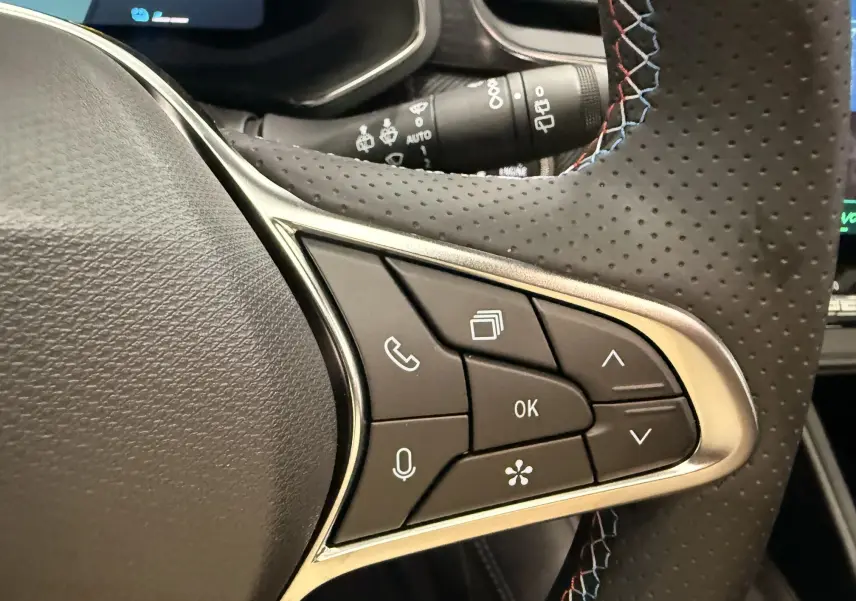 Gros plan sur les commandes multifonctions côté gauche du volant perforé avec surpiqûres tricolores du Renault Symbioz gris Rafale.
