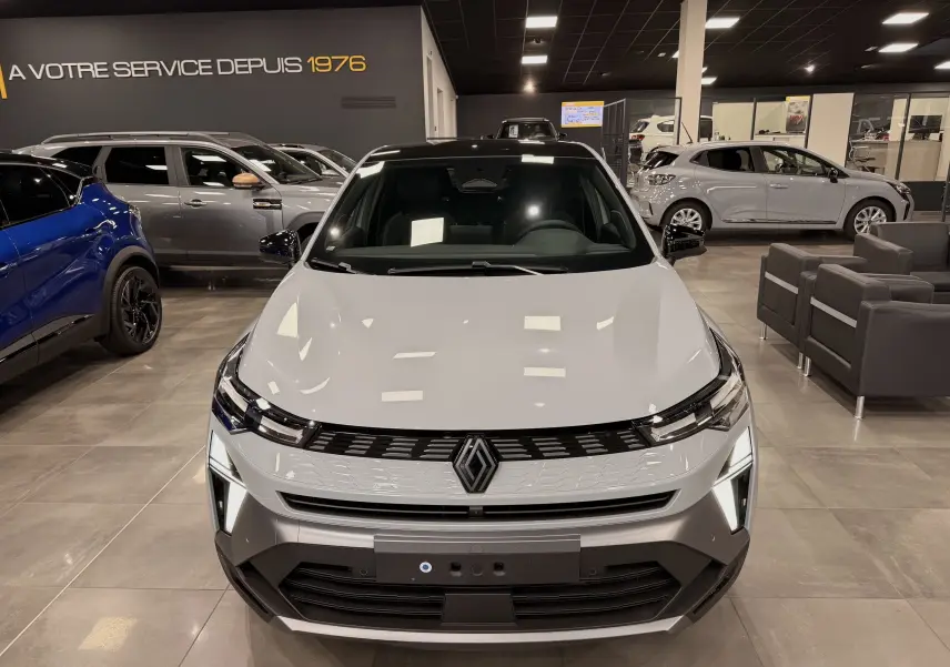Vue avant d'une Renault SYMBIOZ E-Tech full hybrid gris Rafale en showroom, avec éclairage LED distinctif allumé.