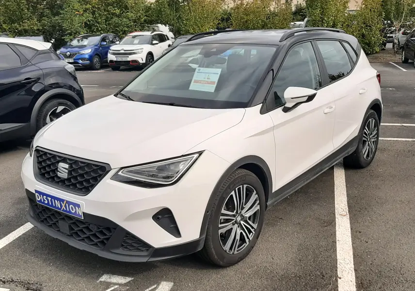 SEAT Arona blanc avec toit noir, vue 3/4 avant droit, stationné sur un parking extérieur.