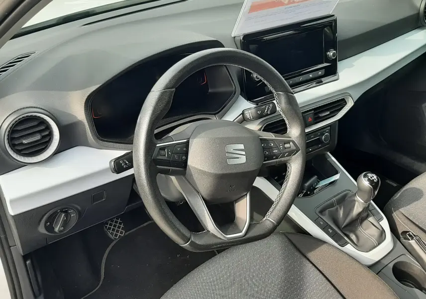 Vue intérieure du poste de conduite de la SEAT Arona 2024, volant multifonction et levier de vitesse manuel visibles.