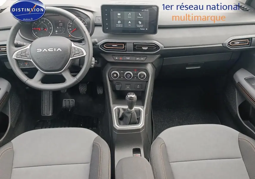 Vue intérieure avant de la Dacia Sandero noire 2025, volant multifonctions, écran tactile et boîte manuelle visible.