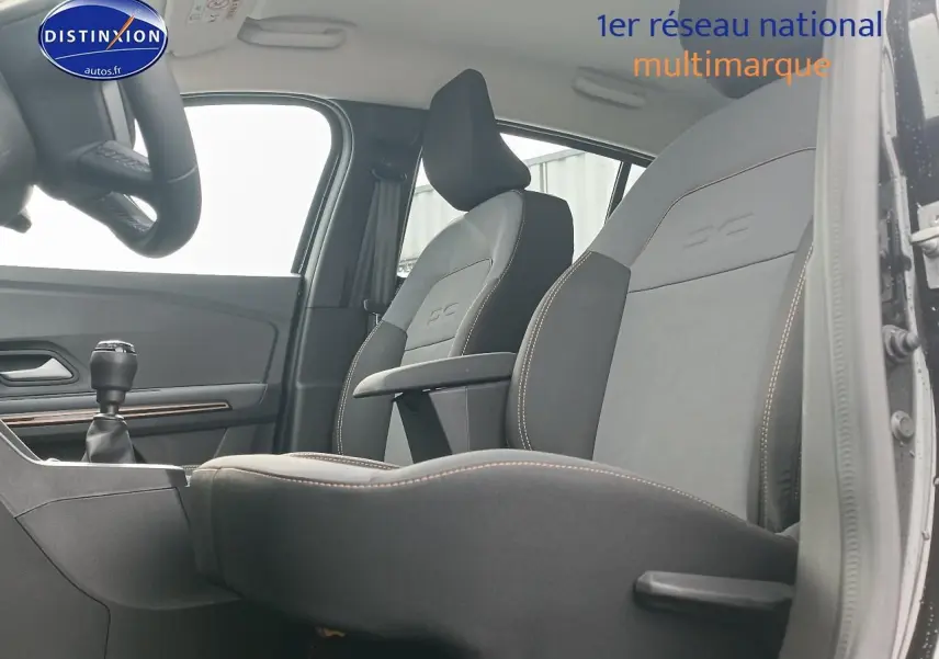 Vue intérieure côté gauche montrant les sièges avant noirs avec accoudoir central de la Dacia Sandero Stepway 2025.