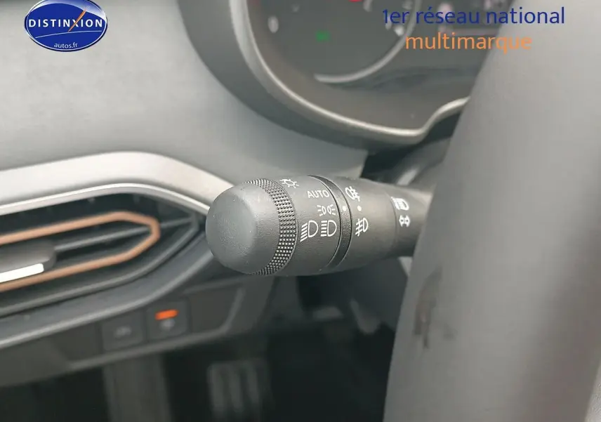 Gros plan sur la commande des phares à gauche du volant dans l’habitacle noir du Dacia Sandero 2025.