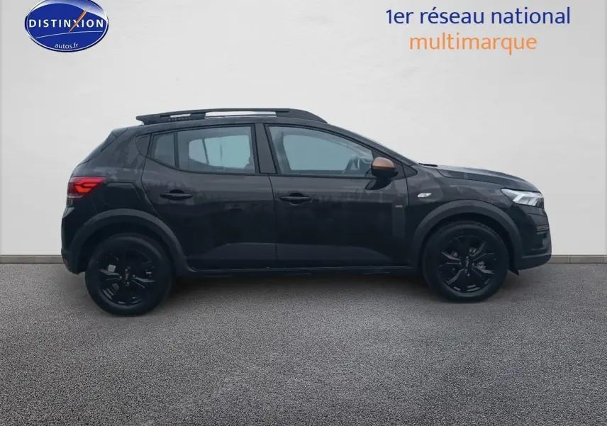 Profil côté gauche de la Dacia Sandero Stepway noire 2025 avec barres de toit et jantes alu noires.