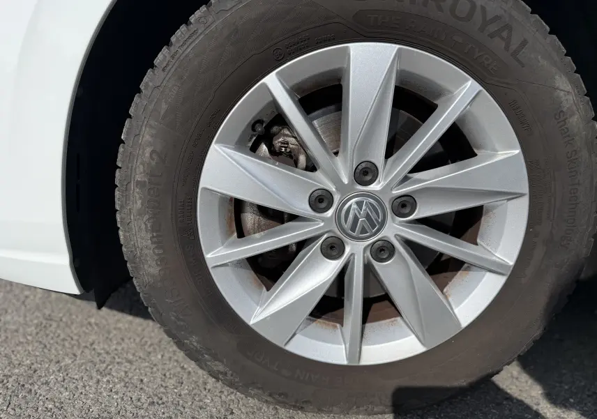 Gros plan sur la roue avant gauche d’une Volkswagen Golf blanche 1.0 TSI 110 LIFE avec jante argentée et pneu Uniroyal.