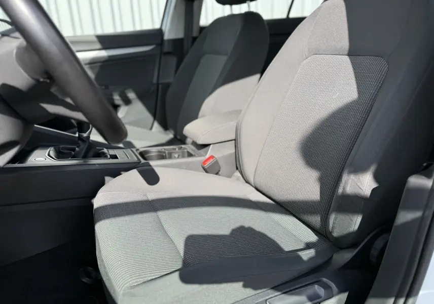 Gros plan sur les sièges avant en tissu gris de la Volkswagen Golf 1.0 TSI 110 LIFE, avec levier de vitesses manuel visible.