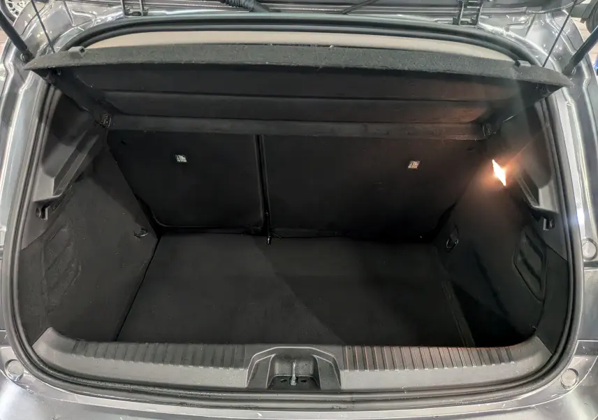 Coffre ouvert vu de l'arrière d'une Renault Clio V gris schiste, montrant l'espace de rangement et l'éclairage intérieur.