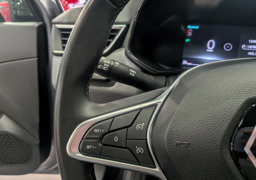 Gros plan sur le volant noir de la Renault Clio V 2024, montrant les commandes de régulateur de vitesse à gauche.