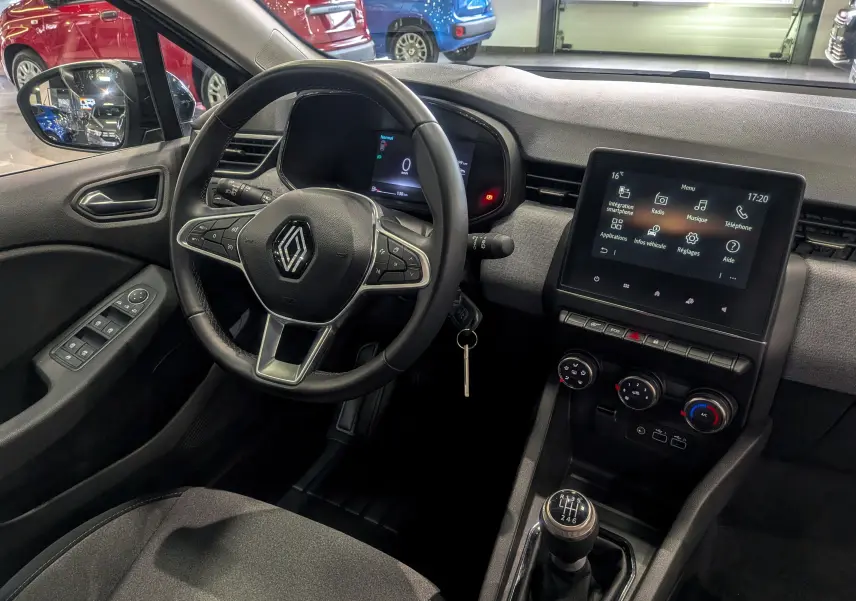 Vue intérieure côté conducteur de la Renault Clio V TCe 90 Evolution 2024, tableau de bord gris avec écran tactile et boîte manuelle.